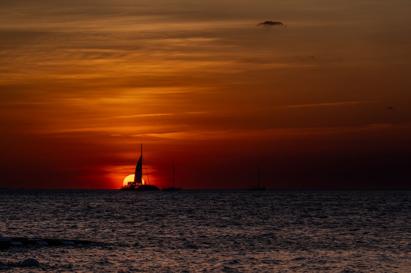 Sailboat silhouetted against vibrant sunset over the ocean in Key West