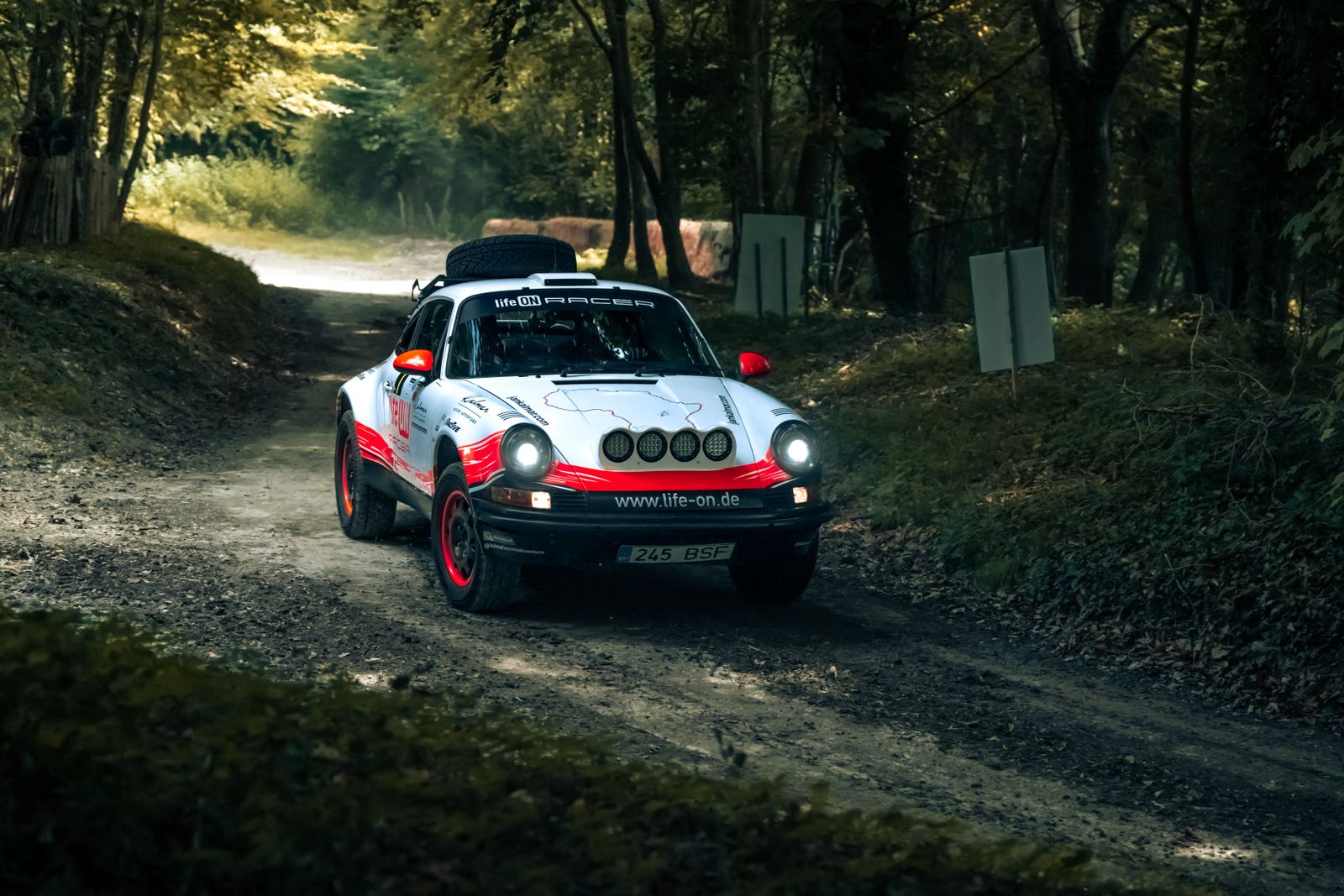 Vintage rally car driving through a scenic forest path