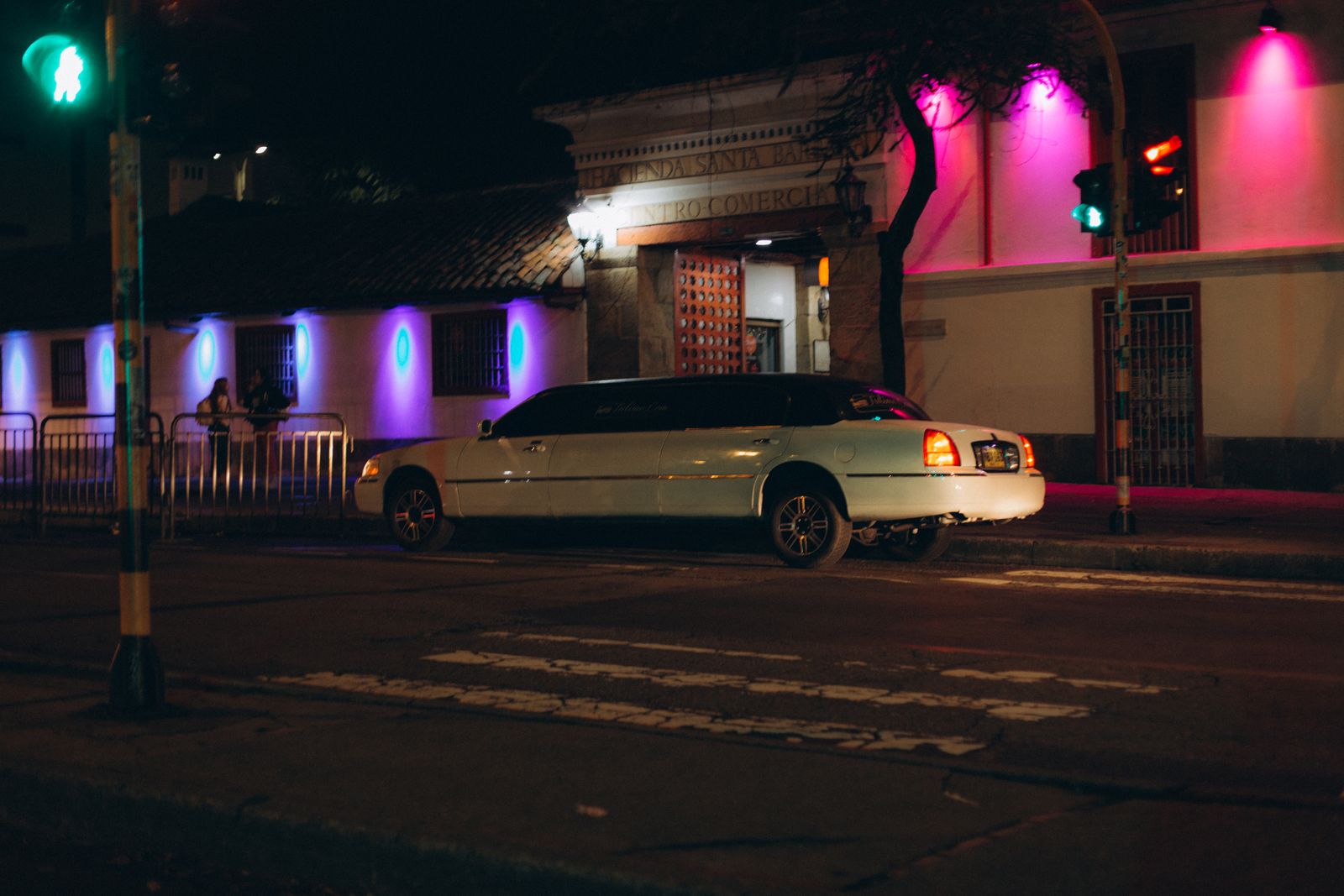 White limousine parked on a city street at night with neon lights